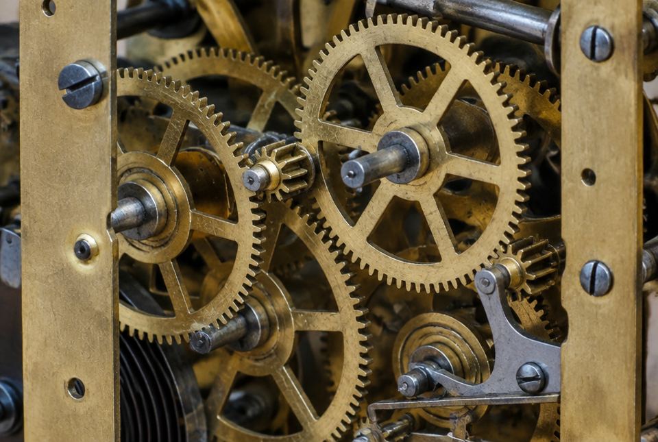 Close-up of brass gears inside a mechanical clock, with their teeth meshing together.